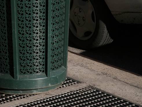 Hubcab, tire, rrash can and subway grate harmonize a pattern
